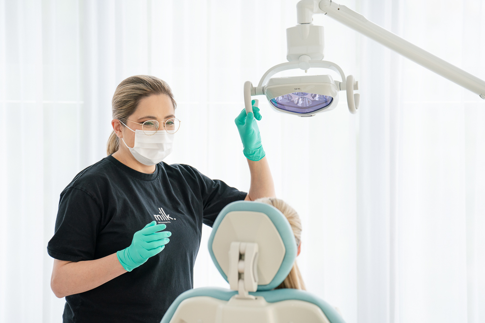 A Milk Orthodontics team member in mask and gloves adjusting the treatment light